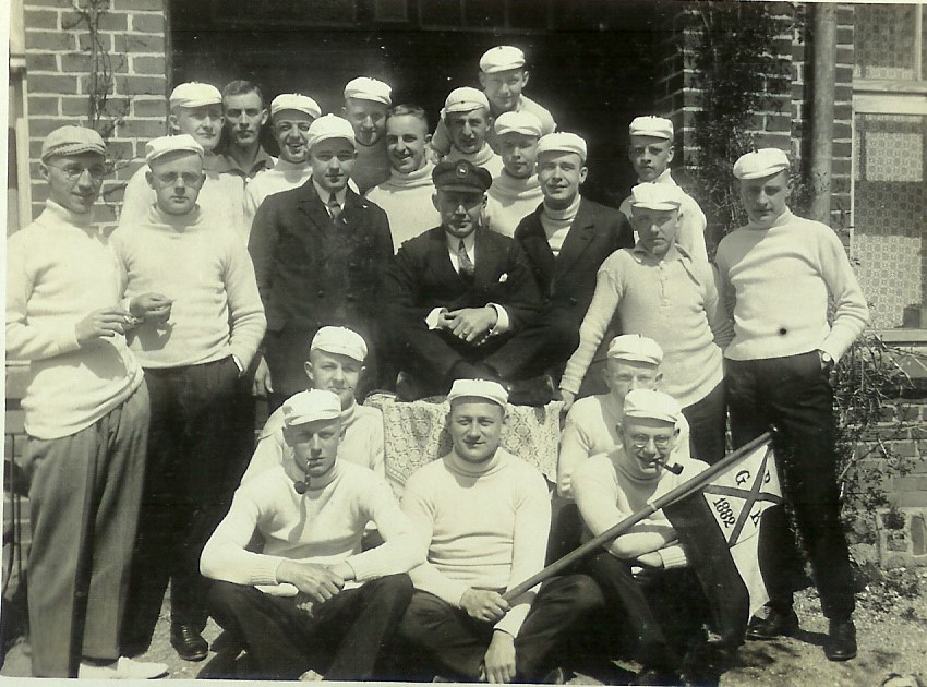 Archivfoto von 1925 mit einer Männergruppe in einheitlicher Ruderkleidung vor dem Tor ins Bootshaus