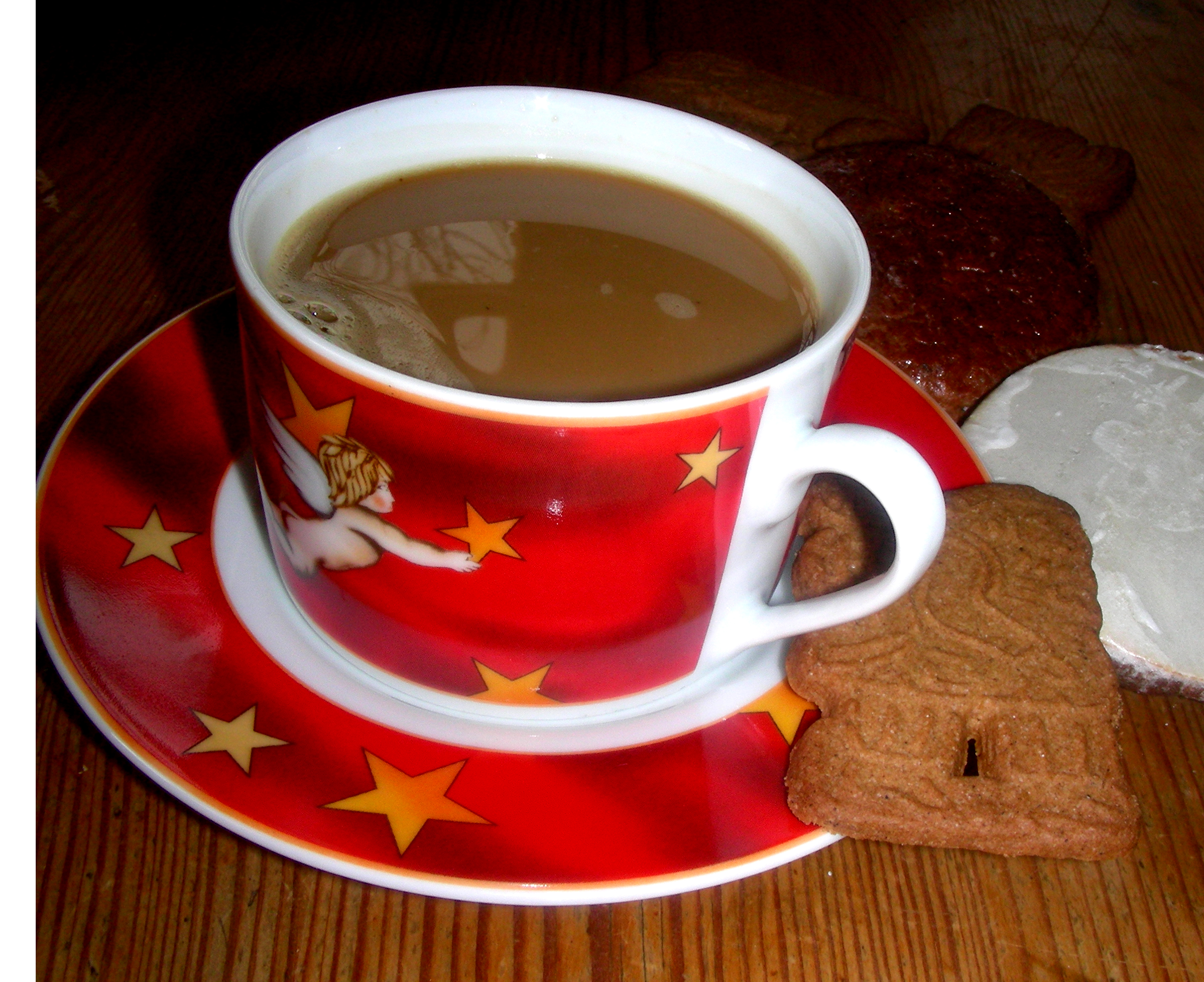 Kaffeetasse im Weihnachtsdekor mit Milchkaffee gefüllt. Auf der Untertasse liegt ein Spekulatius-Keks.